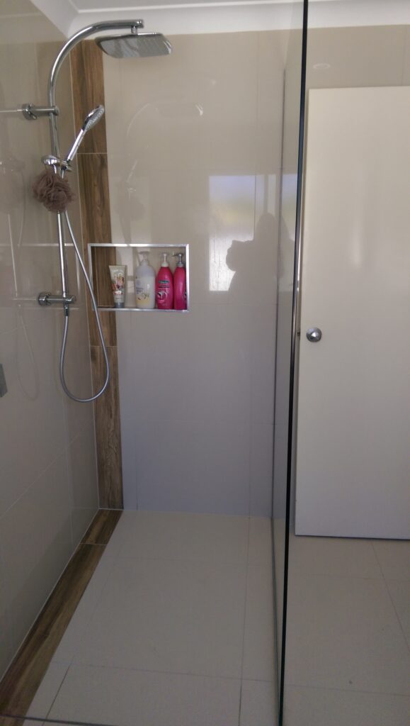 Tiled shower enclosure with glass wall